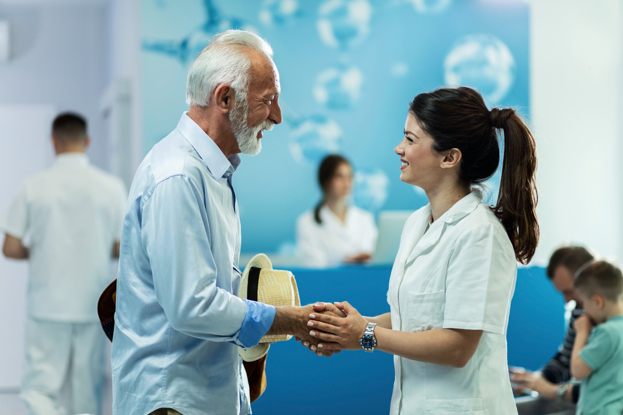 happy-senior-man-handshaking-with-female-doctor-while-talking-lobby-clinic happy-senior-man-handshaking-with-female-doctor-while-talking-lobby-clinic